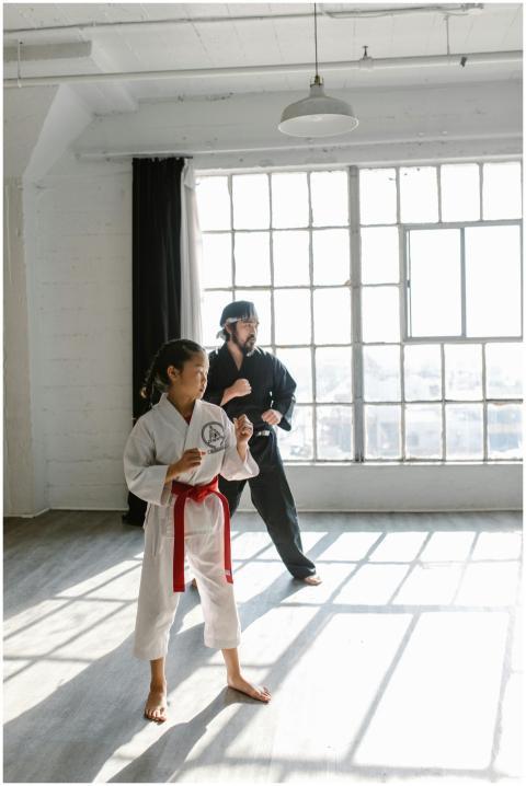 Asian girl with red belt and sensei practicing mar