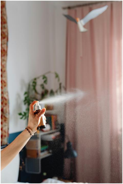 A woman's hand spraying fragrance in a cozy domest