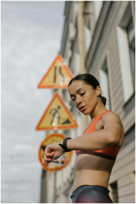 Fit woman in activewear checks her watch on an urb