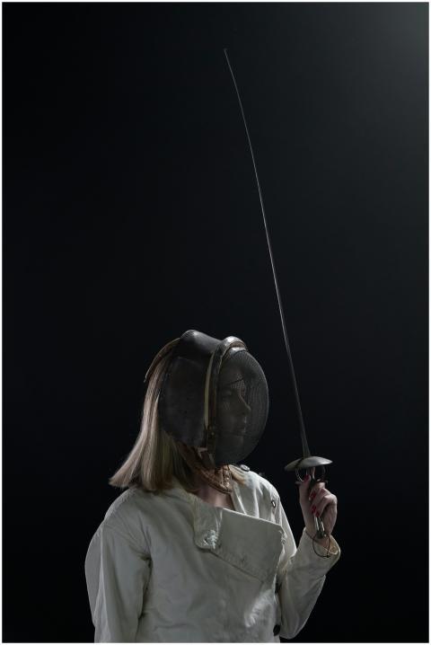 Dramatic portrait of a female fencer holding a swo