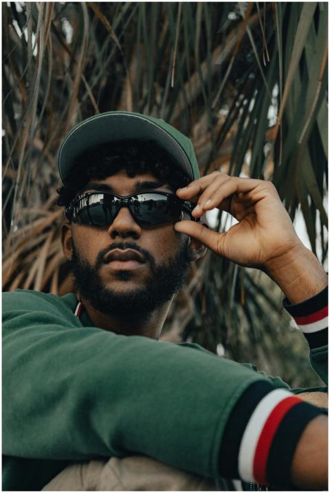 A fashionable man with sunglasses poses outdoors w