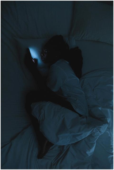 A woman lying in bed at night using a smartphone i