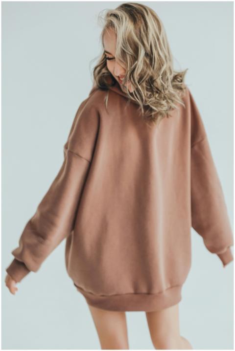 Blonde woman in oversized hoodie smiling and posin