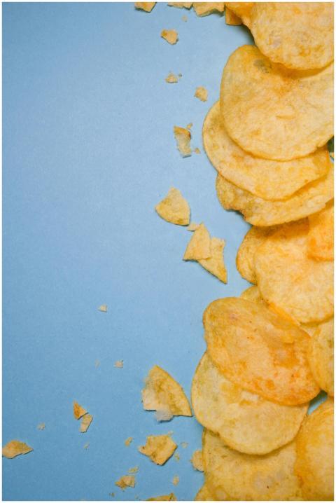 Top view of tasty golden potato chips on blue surf