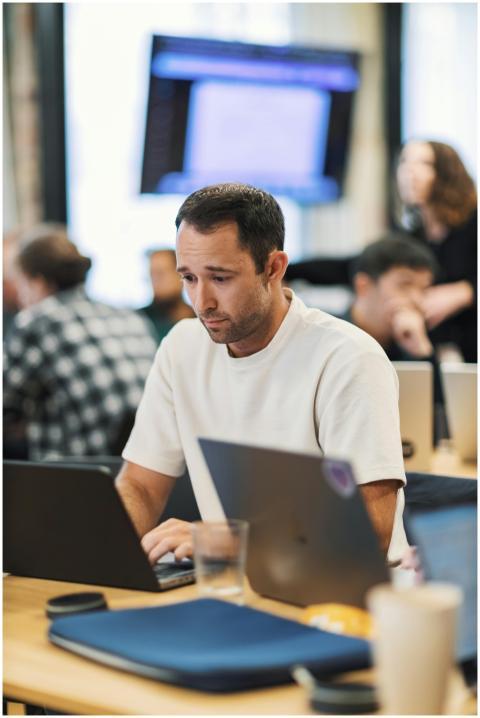 A focused adult male working on a laptop in a mode