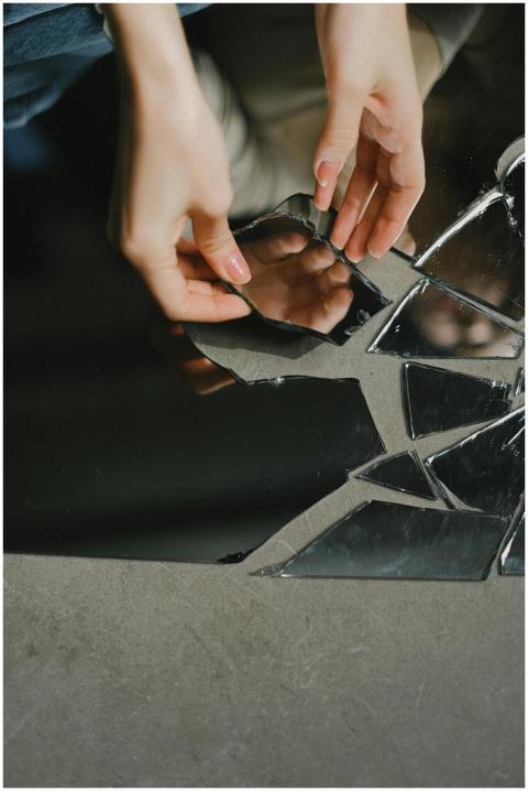 Close-up of hands touching reflective mirror shard