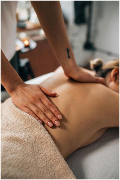 Close-up of hands massaging a person's back in a t