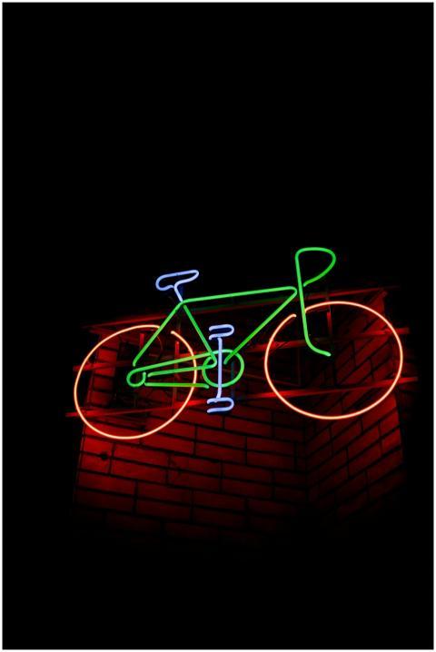 A bright neon bicycle sign glowing against a dark