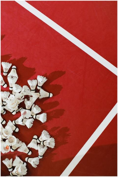 A collection of shuttlecocks spread on a red badmi