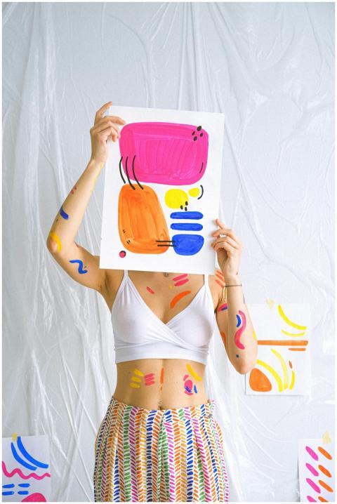 Bright abstract art piece held by decorated woman,