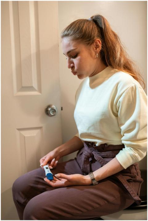 A woman sits indoors, looking intently at a positi