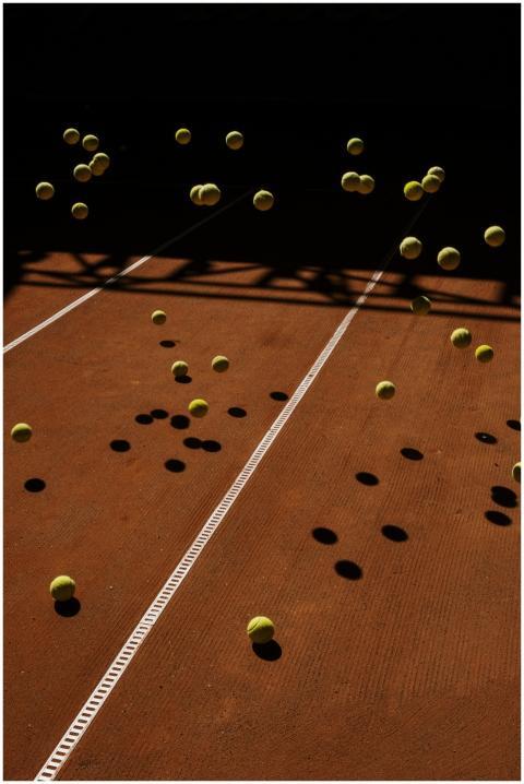 Tennis balls in mid-air on a clay court create a d