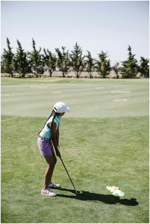 A child golfer prepares a swing on a sunny day on