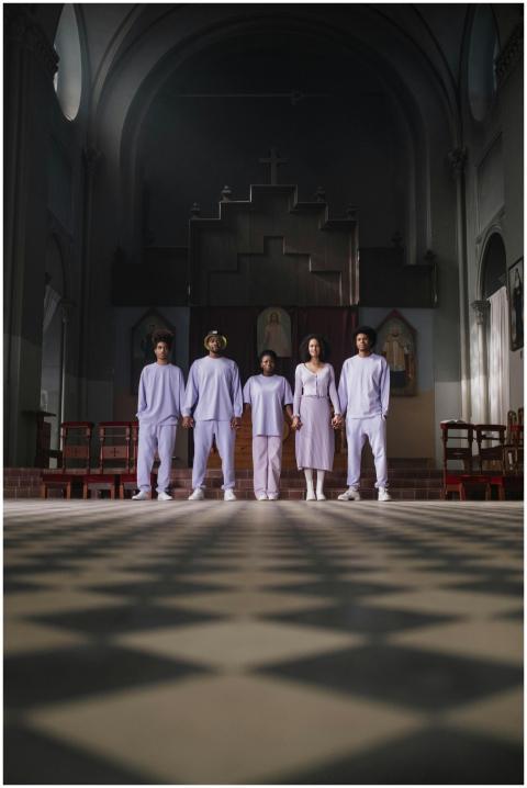 A choir stands united in a church, holding hands i