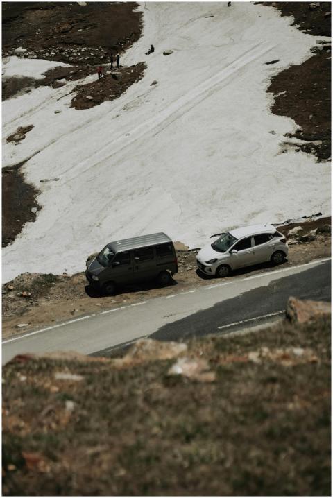 Two vehicles parked by a snowy mountain roadside d