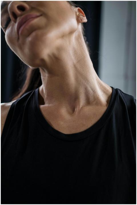 Close-up of a woman stretching her neck in a black