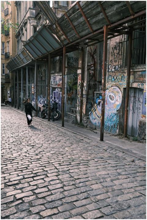 A person walks along a graffiti-covered street wit