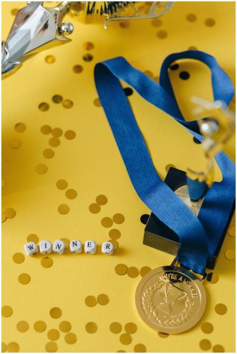 Gold medal and winner's trophy on a vibrant yellow