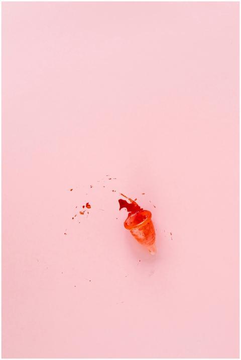Menstrual cup with spilled blood on a pink backgro
