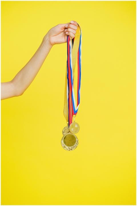 A hand holding multiple gold medals with colorful