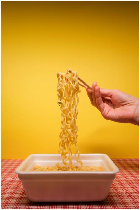 Crop anonymous person using bamboo chopsticks whil
