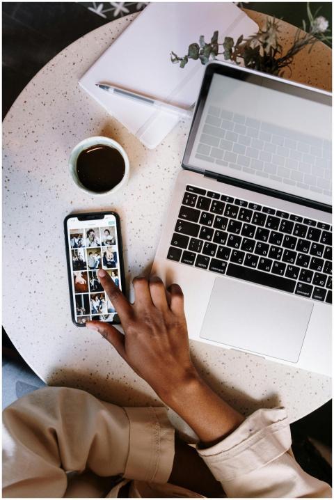Person interacting with smartphone and laptop at a
