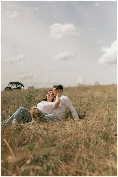 A couple embraces on a sunny day in a grassy meado