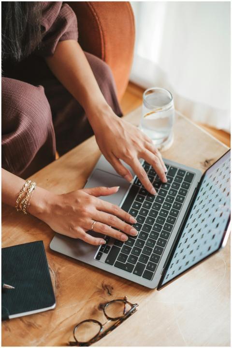 Close-up of a woman typing on a laptop with eyegla