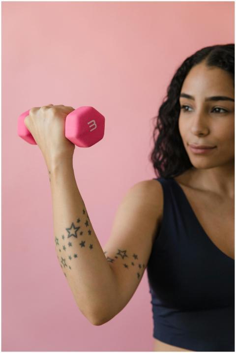 A woman exercising with a pink dumbbell, showcasin