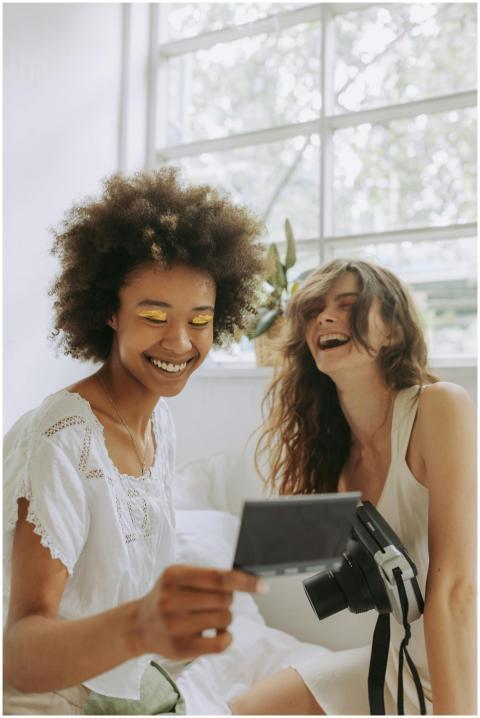 Two friends laughing while looking at instant phot