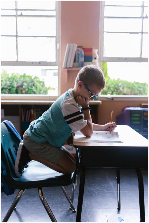 A young boy diligently doing homework at a classro