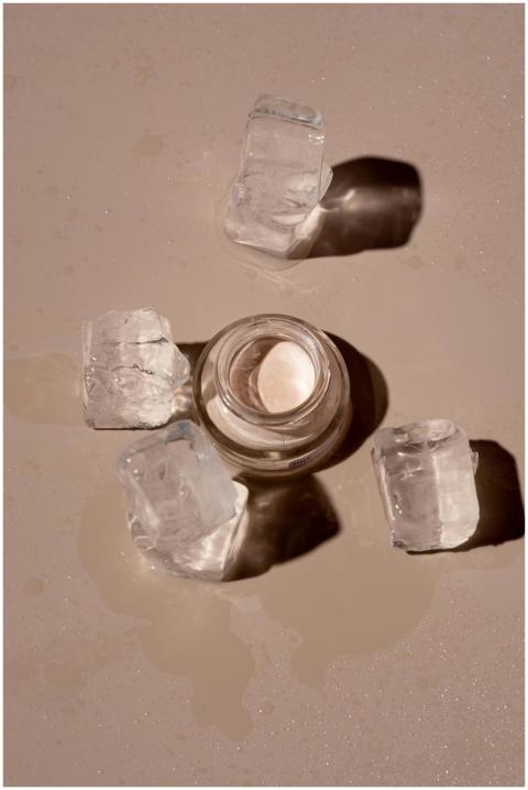 Flat lay of a skincare product surrounded by ice c