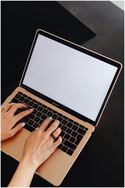 Close-up of hands typing on a MacBook with an empt