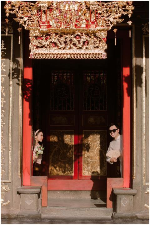 Two people peering from a traditional Asian temple