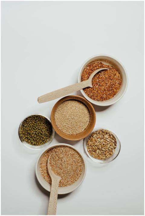Top view of assorted grains in bowls with wooden s