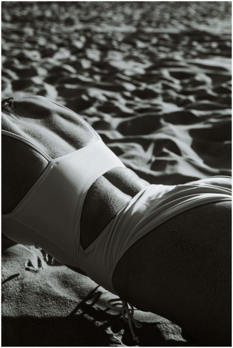 A grayscale image of a woman in a swimsuit lying o