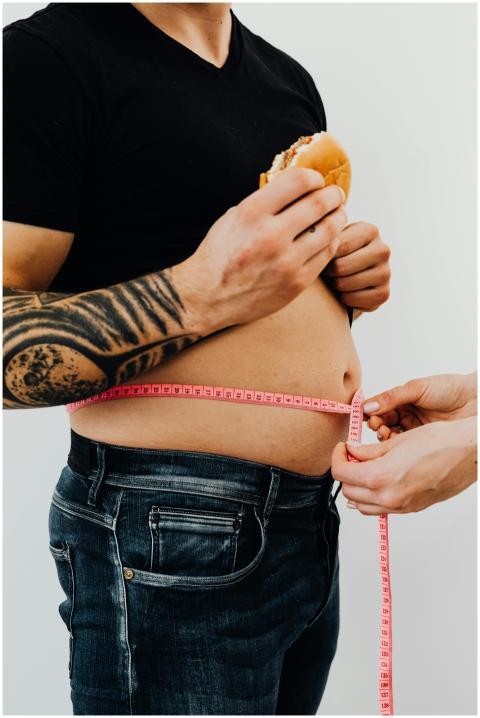 Close-up of a man holding a burger while measuring