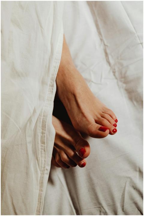 Close-up of feet with red pedicure peeking out fro