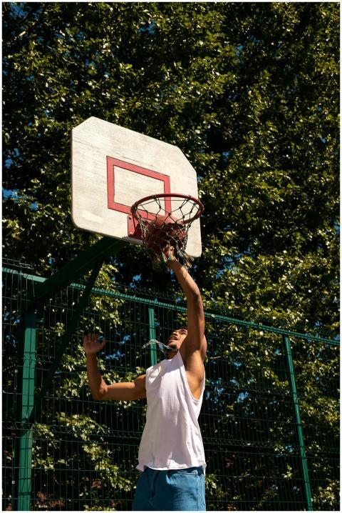 A young man shooting hoops on a sunny day with lus
