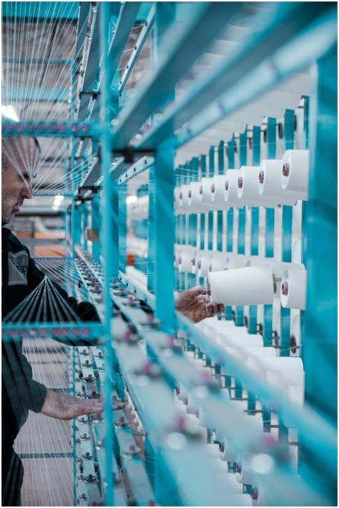 A textile factory worker inspects spools of thread