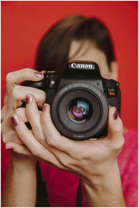 Woman holding a camera with a red background, read