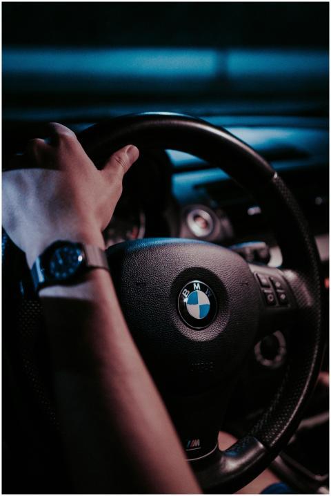 Close-up of a hand on a BMW steering wheel at nigh