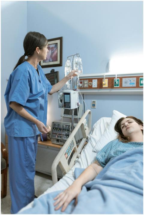 A nurse attends to a patient in a hospital room, e