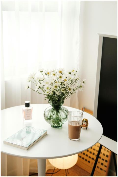 A minimalist setup with white daisies, perfume, an