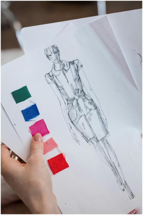 Close-up of a hand holding a fashion sketch with v