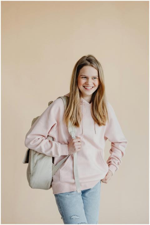 A cheerful teenage girl standing with a backpack r