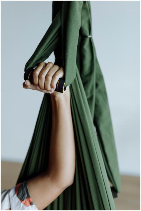 Close-up of a hand gripping a green aerial yoga ha