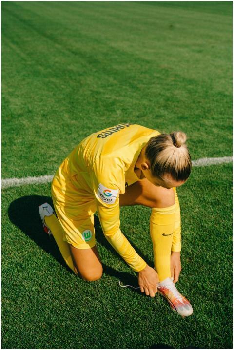 A female soccer player in yellow sportswear tying