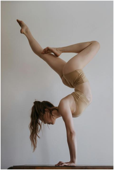 Woman performing a handstand indoors wearing neutr