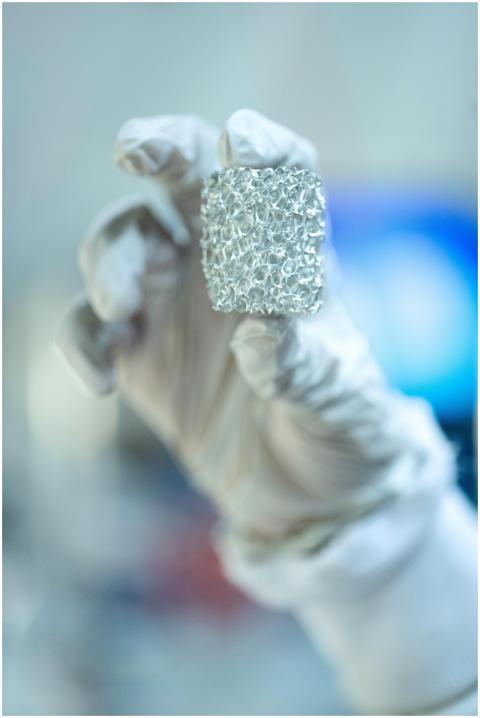 Close-up of a scientist holding metallic foam in a